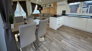 Una cocina moderna con armarios blancos, un comedor con mesa y sillas, y un ventanal con vistas al exterior.