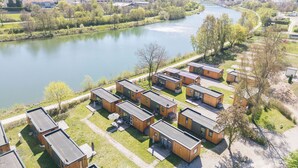 A lakeside property with modern cabins, a river, and a hilly backdrop. - Tiny Haus Altmühlpanorama by Interhome (Riedenburg)