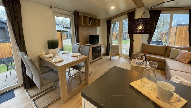 A modern living room with a sofa, a dining table set for two, a TV, and a fireplace. - Tiny Haus Altmühlpanorama by Interhome (Riedenburg)
