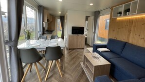 A modern RV interior with a dining area, a sofa, and a TV. - Tiny Haus Flussblick by Interhome (Riedenburg)