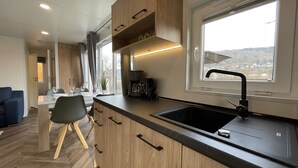 A modern kitchen with wooden cabinets, a black countertop, and a large window. - Tiny Haus Flussblick by Interhome (Riedenburg)