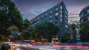 Un hôtel moderne à la façade sombre, avec de nombreux étages et une enseigne bien visible.