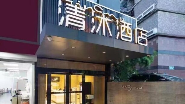 L’entrée d’un hôtel au design moderne, avec une grande enseigne lumineuse et une porte d’entrée en verre.