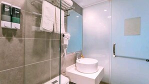 Une salle de bain moderne avec une douche à parois de verre, un lavabo blanc et un porte-serviettes avec plusieurs serviettes.