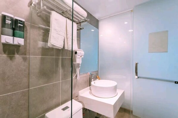 A modern bathroom with a glass shower enclosure, a white sink, and a towel rack with multiple towels. - Qingmu Hotel (Nanjing)