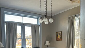 Een slaapkamer met een bed, nachtkastjes, een lamp, een raam met gordijnen en een plafondventilator.