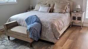 Een slaapkamer met een bed, een plafondventilator, een nachtkastje, een lamp en een raam.