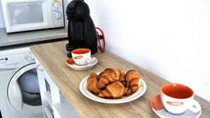 Una kitchenette equipada con microondas, cafetera y lavadora.