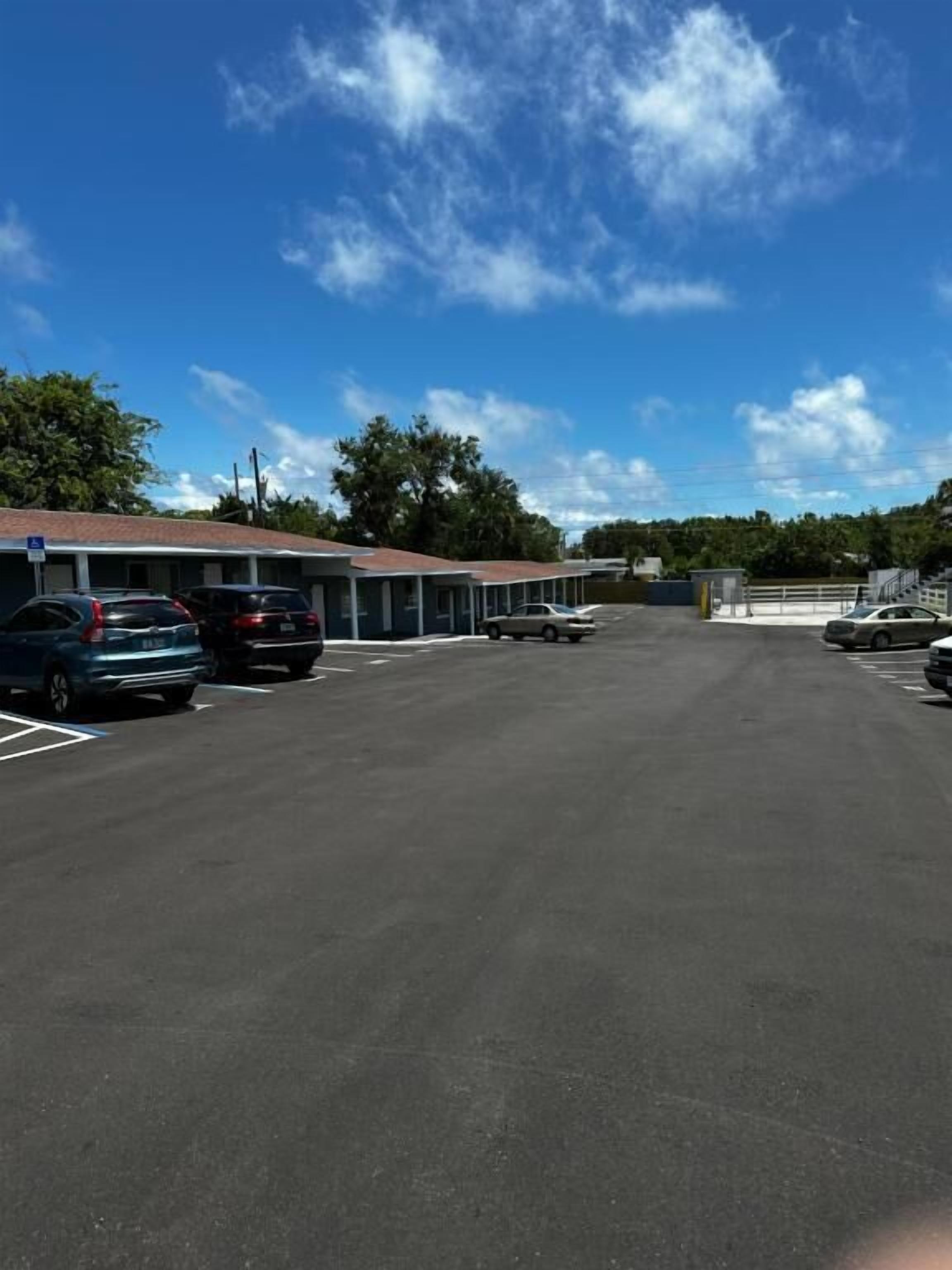 A parking lot with several cars parked in front of a motel with a red roof.
