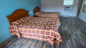 A room with two beds, a window with blinds, and a built-in air conditioning unit. - Red Carpet Inn (Daytona Beach)