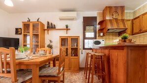 A kitchen with wooden cabinets, a dining table with chairs, a microwave, and a clock on the wall. - Tu y Yo by Interhome (Deltebre)