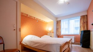 A single bed in a room with wooden flooring, a chair, a radiator, and a window with curtains. - Centrally located by Interhome (Blankenberge)