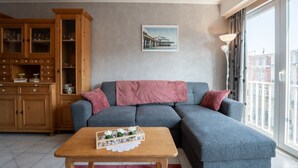 A modern living room with a grey sectional sofa, wooden cabinet, and a wooden coffee table with decorative items. - Centrally located by Interhome (Blankenberge)