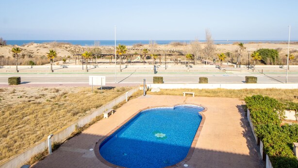 Uma piscina com vista para a praia e dunas.
