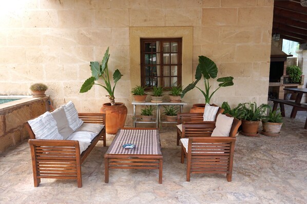 An outdoor patio with wooden furniture, including a sofa and chairs, a table, and several potted plants. - 1 bedroom villa with private pool and barbecue (Moscari)