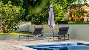 A swimming pool with two lounge chairs and a covered umbrella. - Vacation home Ulika by Interhome (Poreč/Baderna)