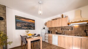 A modern kitchen with wooden cabinets, a dining area with a table and chairs, and a cityscape painting on the wall. - Vacation home Ulika by Interhome (Poreč/Baderna)