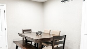 A dining area with a wooden table and chairs, a ceiling fan, and a white textured wall.