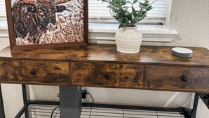 A wooden desk with a framed picture of a bull, a potted plant, and a stack of plates.