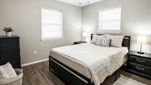 A bedroom with a bed, bedside tables, a ceiling fan, and a window.