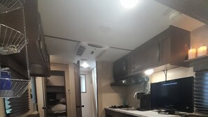Cocina compacta con encimera de mármol, horno integrado y microondas. Hay una pequeña isla con salero y un cuaderno.