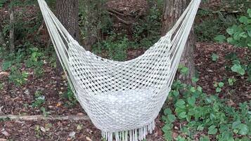 A white hammock suspended between trees in a forest.