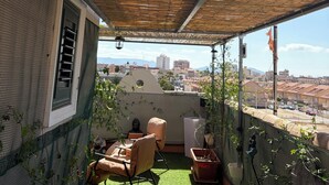 Un espace extérieur abrité comprenant une chaise, une table et des plantes en pot.