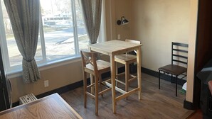 Una habitación con ventana, una mesa, dos sillas, una lámpara y un radiador.