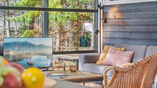 A modern living room with a large window, a sofa, a wicker chair, and a coffee table with books and a candle. - "Ela" - 800m from the sea by Interhome (Vig)