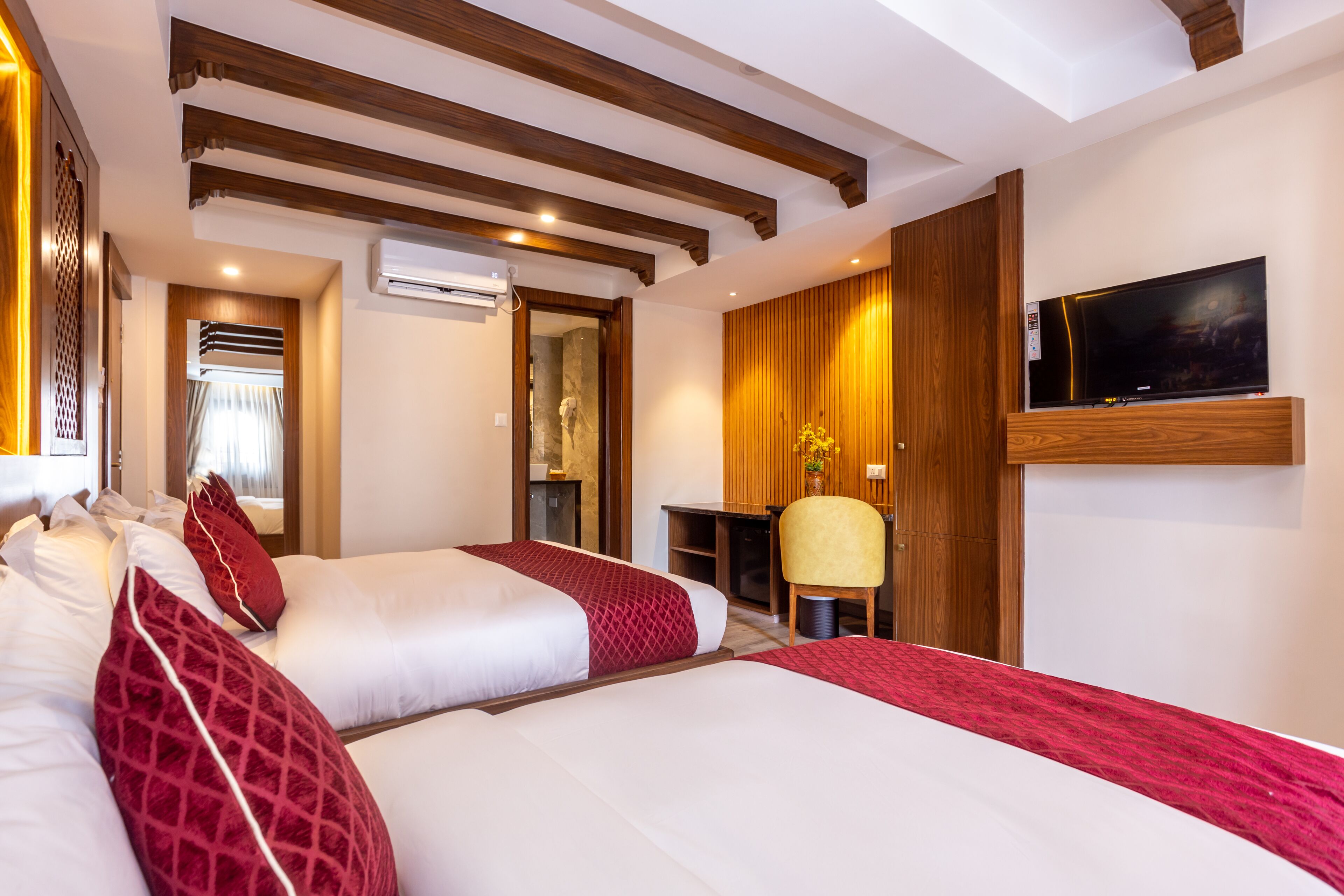 Une chambre d’hôtel avec deux lits, une télévision, un bureau et une chaise.