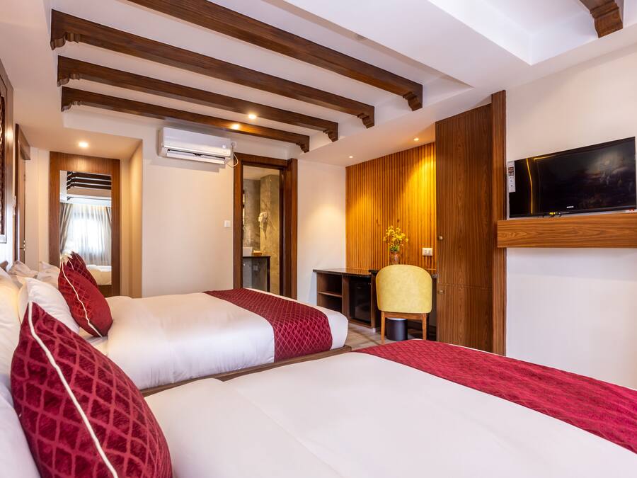 Une chambre d’hôtel avec deux lits, une télévision, un bureau et une chaise.