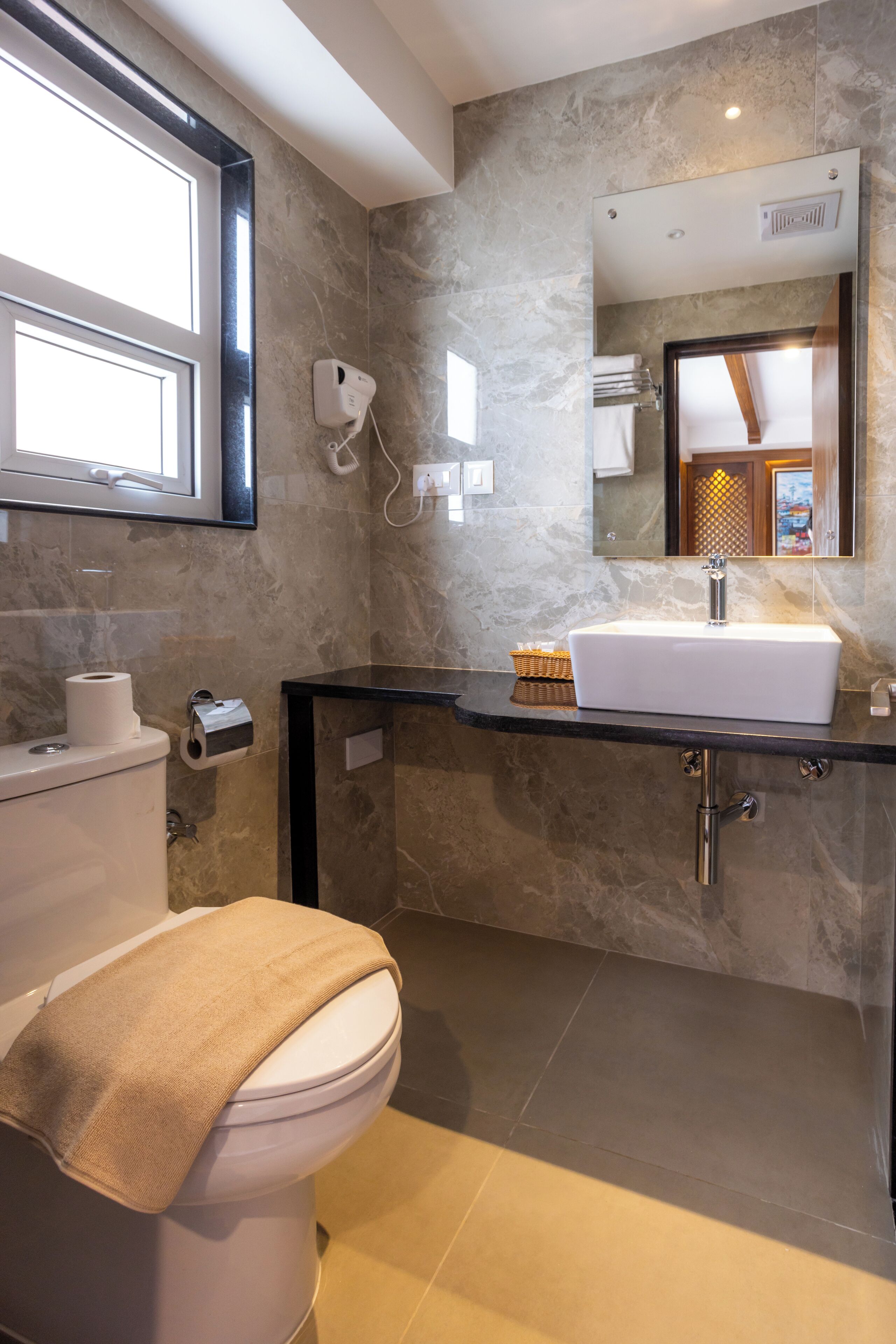 Un baño moderno con pared de mármol, un lavamanos blanco y un inodoro.