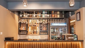 Zona de bar con estantes llenos de botellas de licor, vasos y una máquina de café.