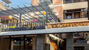 Un edificio de varios pisos con fachada de vidrio, un área de entrada cubierta con plantas y un letrero que dice "KALASH BOUTIQUE".
