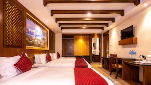 Habitación de hotel con dos camas, techo de madera, un cuadro, un escritorio y un televisor.