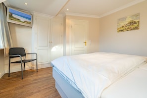 Une chambre à coucher avec un lit, une chaise, un téléviseur et une porte.