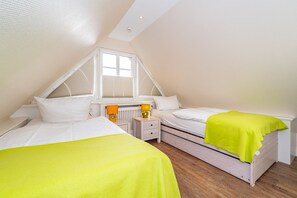 Un dormitorio con dos camas, una ventana y un radiador.