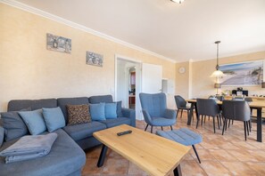 Un salon comprenant un canapé, des fauteuils, une table basse et un coin repas avec des chaises et une table.