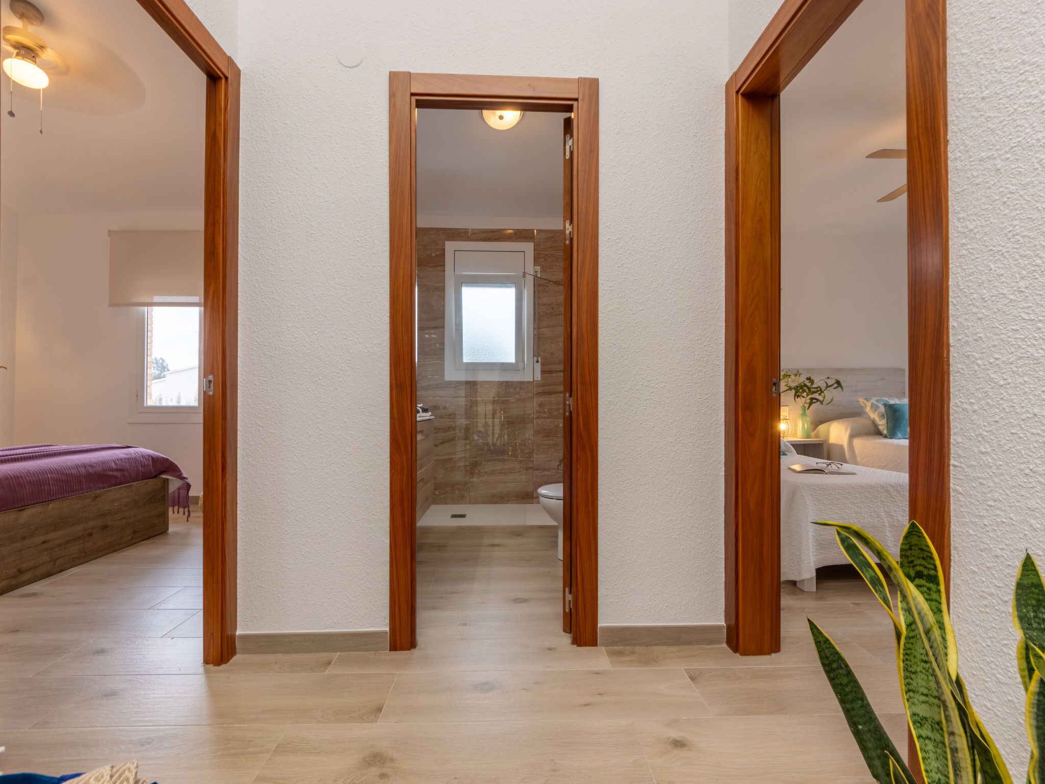 A hallway with wooden doors leading to a bedroom and bathroom.