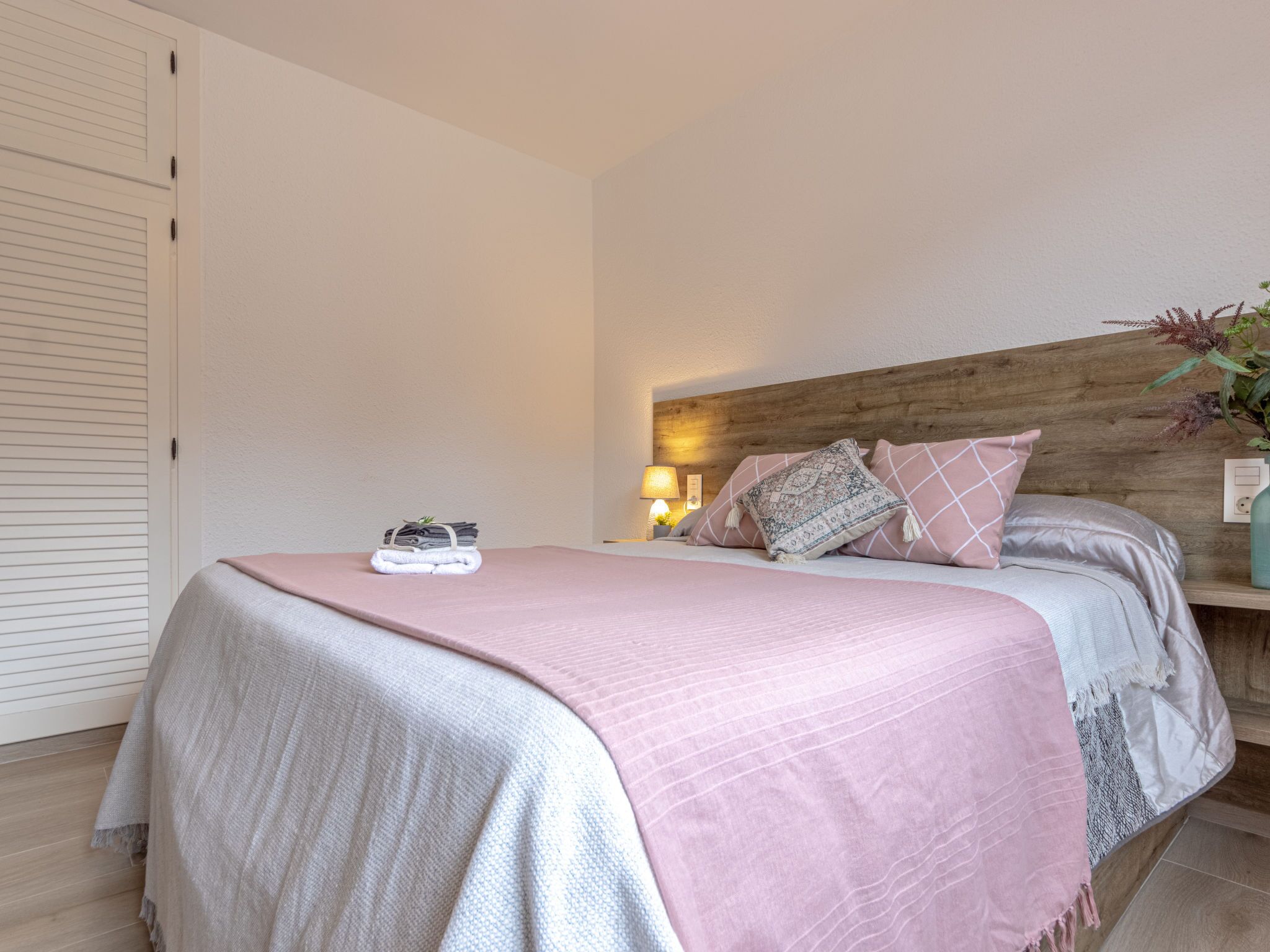 A bedroom with a bed, pillows, a bedside lamp, and a wooden headboard.