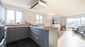 Een moderne keuken met een centraal eiland, grote ramen en uitzicht op de omgeving.