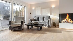 Een moderne woonkamer met een bank, fauteuil en een open haard.