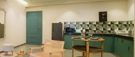 A modern kitchen with green cabinets, a round wooden table, and a blue door.