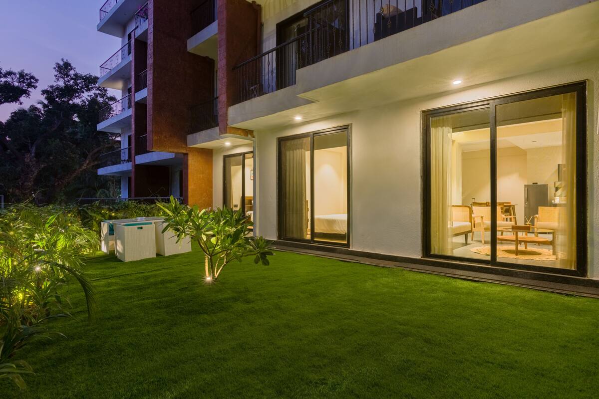 A modern hotel with a well-maintained lawn, large sliding glass doors, and a balcony with railings.