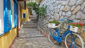 A narrow cobblestone street with a blue bicycle parked against a stone wall, leading up a set of stairs. - Bel Horizonte 7, Capoliveri (Capoliveri)