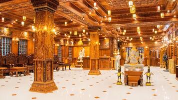 A spacious lobby with ornate columns, a central statue, and a polished floor.