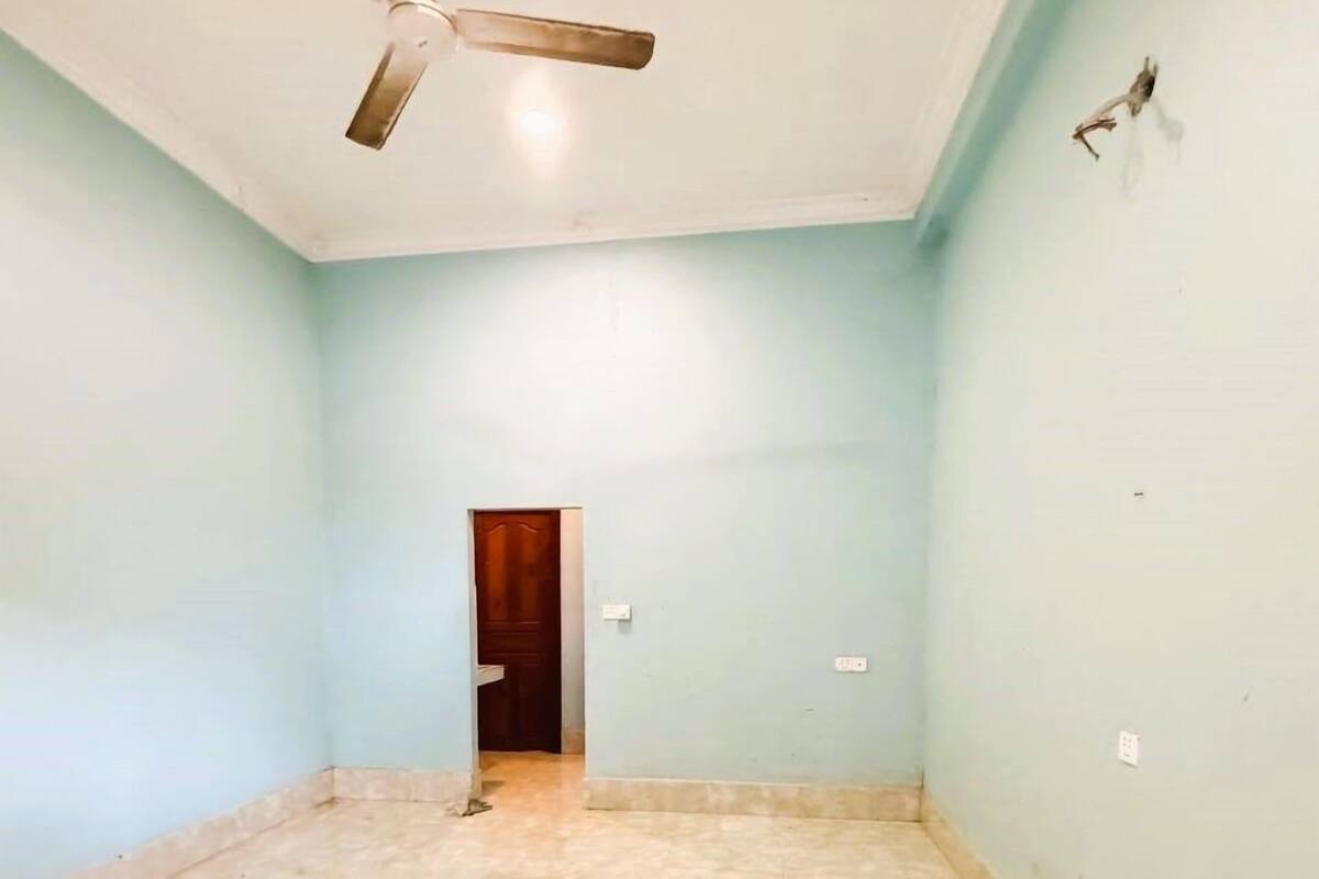 Une pièce spacieuse aux murs bleu clair, dotée d’un sol carrelé et d’un ventilateur de plafond.
