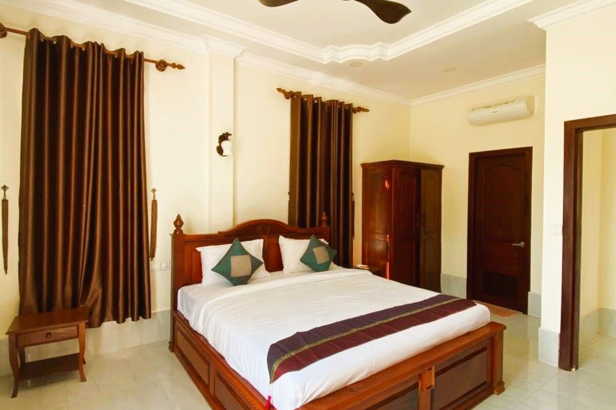 A spacious bedroom with a large bed, wooden headboard, and a ceiling fan.