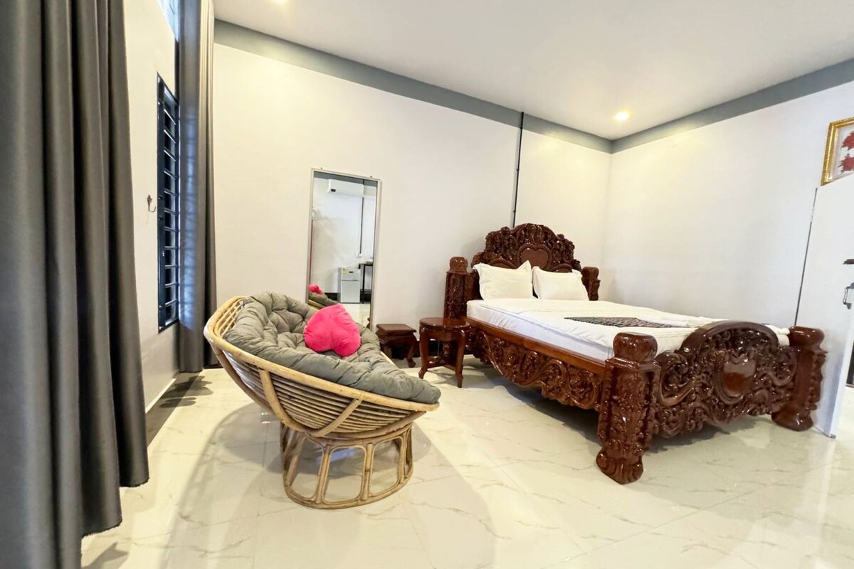 Un dormitorio con una cama grande, una silla de mimbre y un espejo.