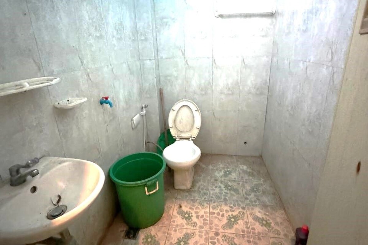 A small bathroom with a sink, toilet, and green bucket.